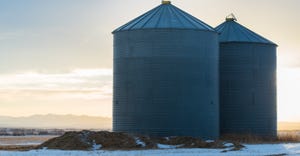 Two grain bins in winter at sunset