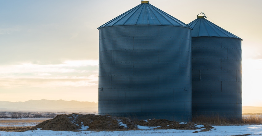 Two grain bins in winter at sunset