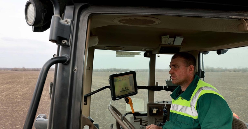 Ukraine Farmer Morda Vasyl drives a tractor pulling a planter to plant sugar beet seeds