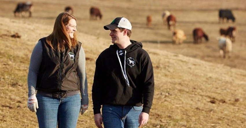 Katie Brenny and her husband, Ted, in a field with Angus cows in background