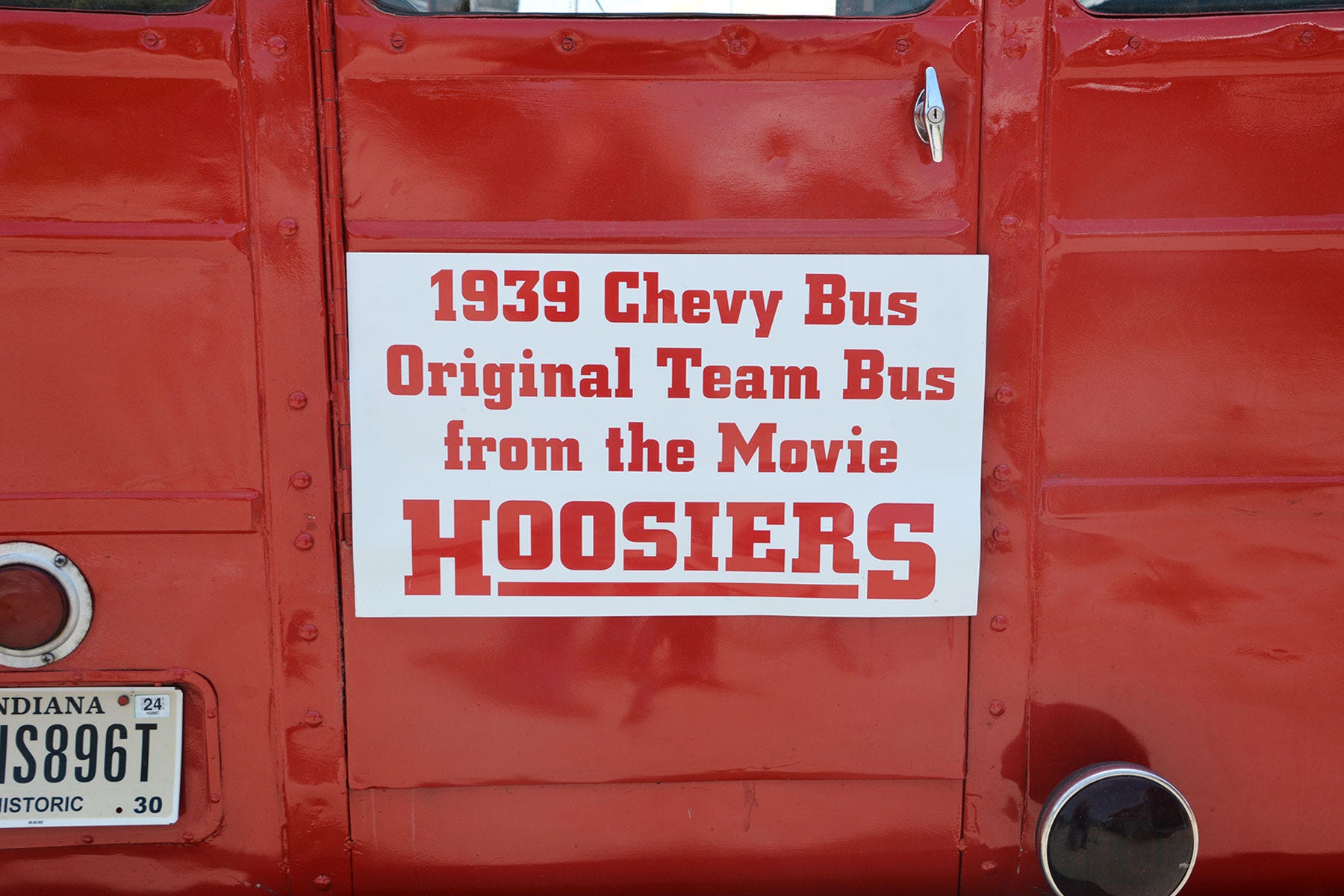 close-up of sign on back of red bus reading: 1939 Chevy Bus Original Team Bus from the Movie Hoosiers