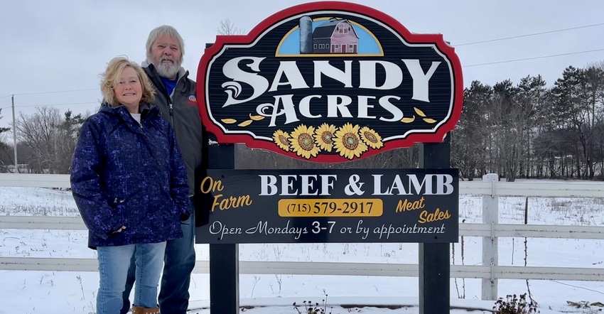 Marie and Jeff Pagenkopf standing next to Sandy Acres Farm sign