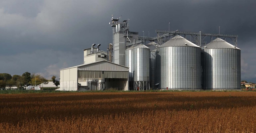 grain bins by brown soybean field grain bins by brown soybean field