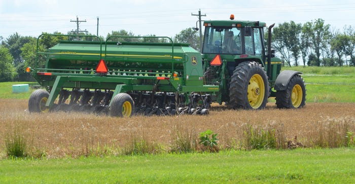 planter in field planting soybeans into wheat