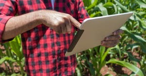 Farmer using digital tablet computer in cultivated corn field 