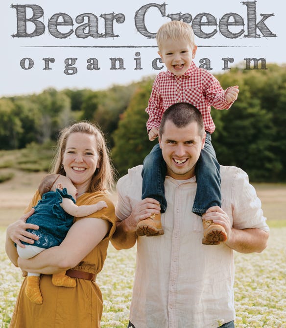 Brian and Anne Bates, owners of Bear Creek Organic Farm, with their children in field
