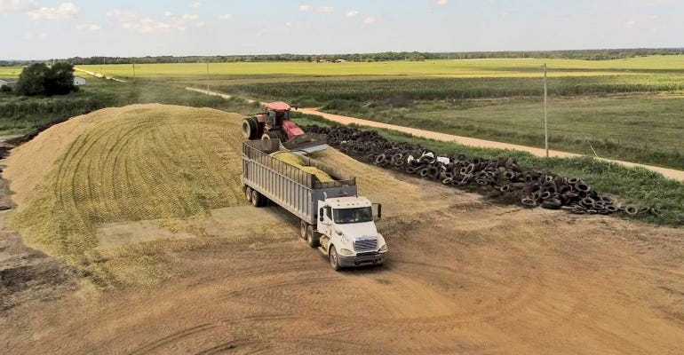 a truck delivers chopped corn to silage pile