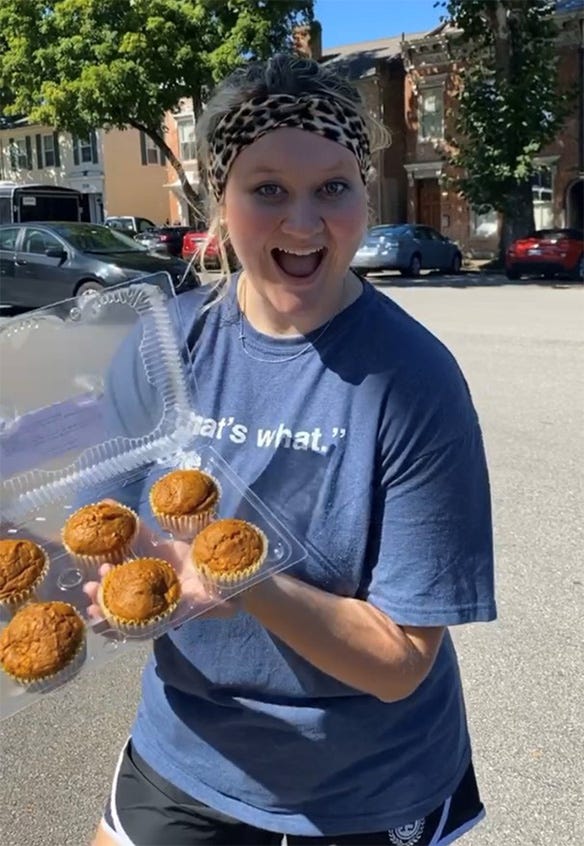 An enthusiastic young woman holding muffins