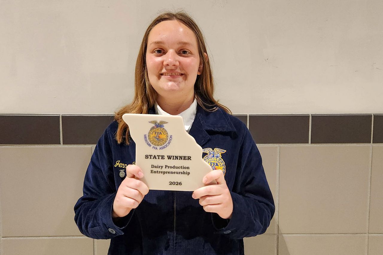 Jenna Brixey holds up her state winner award for dairy production entrepreneurship