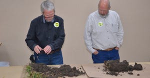 Brian Daggy, left and Curt Emmanuel display a soil from a six-year no-till and cover crop plot vs. soil from the same field i