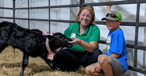 Eileen Jensen and a young volunteer show off a calf