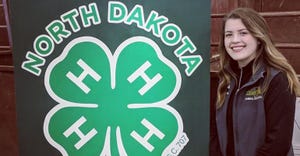  SARAH McNAUGHTON standing next to 4-H North Dakota logo