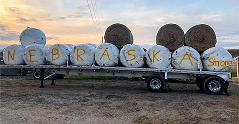 Bales of hay wrapped in plastic on a flatbed truck spell out 'Nebraska Strong' 