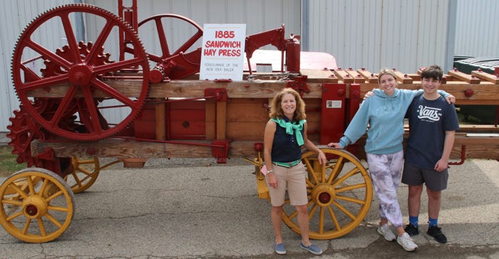 Laura Sniader and her children standing with an 1885 Sandwich Hay Press 