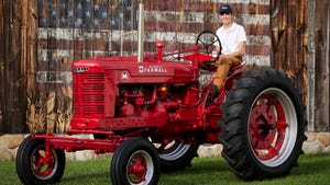Andrew Hanna sits on a restored Farmall tractor
