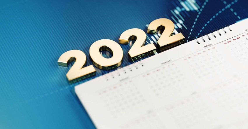 Gold colored 2022 sitting over a white calendar on blue financial graph. Horizontal composition with selective focus and copy
