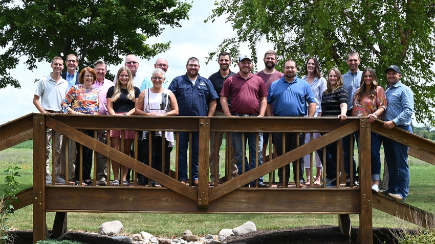 A group of people pose for a photograph as they stand on a wooden bridge