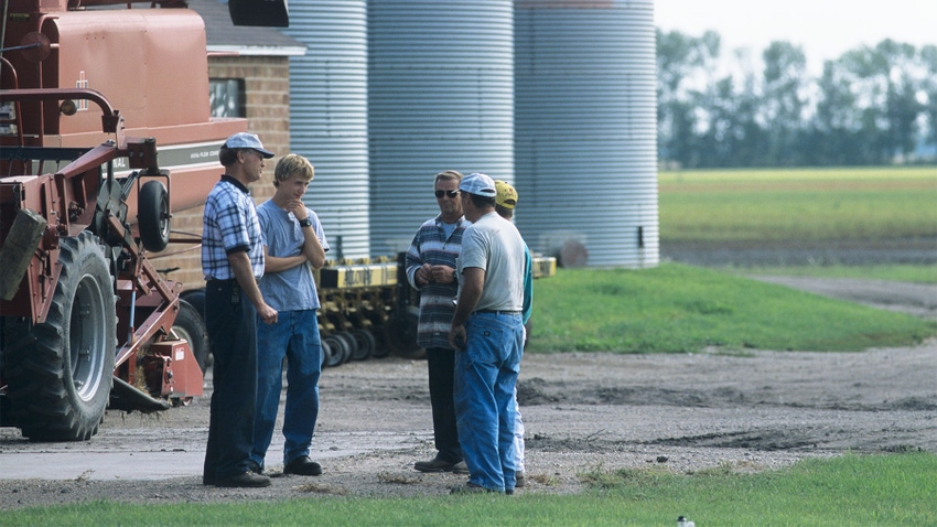 Farmer and hired hands talking near combine