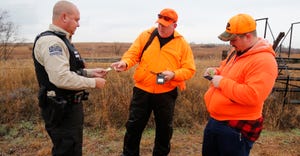  Game warden Jason Barker, left, checks the hunting licenses of Michael and Austin Floyd. 