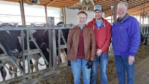 Carol and Eric Hillan and their son, Evan in barn with dairy cows