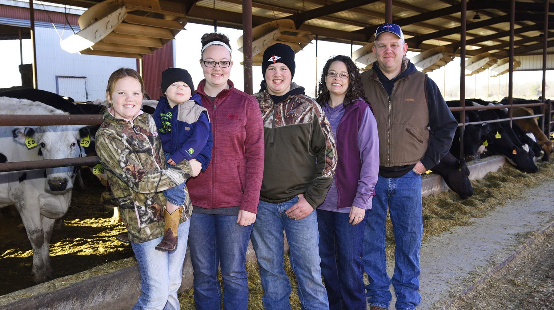 Joann Pipkin - A family gathers together for a photograph in front of dairy cows