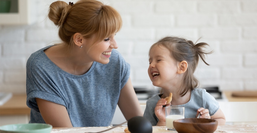 A mother and daughter laughing and eating breakfast
