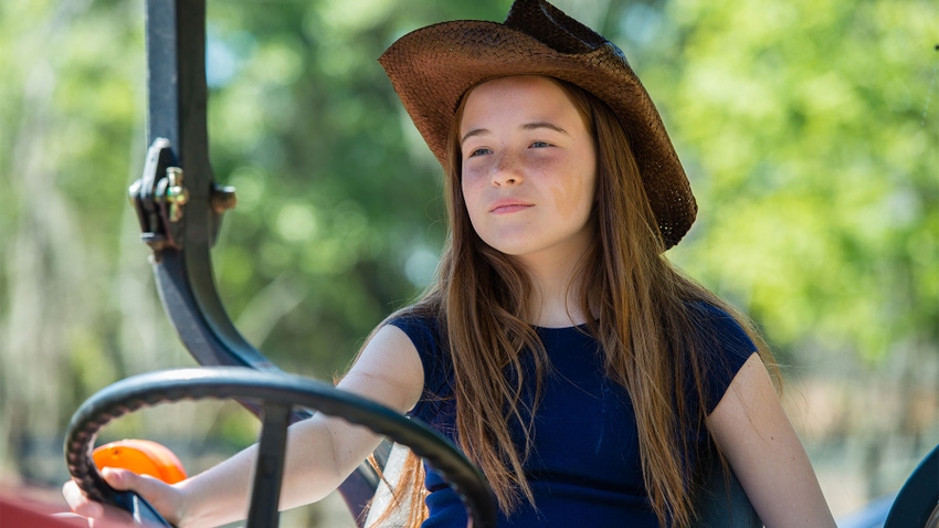 A young farm girl driving a tractor