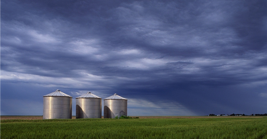 Silos in field under cloudy skies