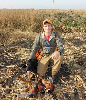 a young male hunter with 3 dead pheasants and black lab