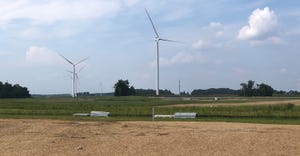 wind turbines loom over solar farm