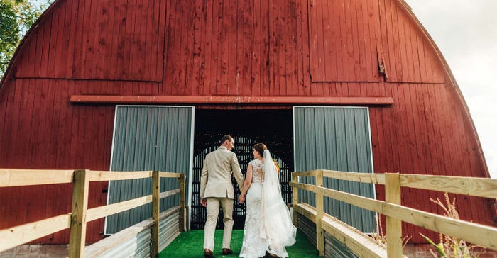 Bride and groom walking up a special ramp built to move round bales to and from the Clark barn became the wedding aisleway