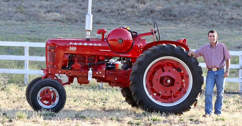 young man standing next to red tractor young man standing next to red tractor