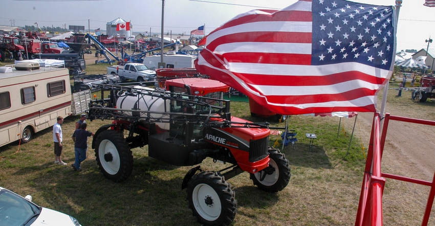 An American flag flying high next to a tractor at an exhibit