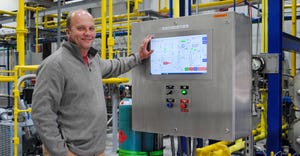 A man smiles as he holds on to a machine's control box