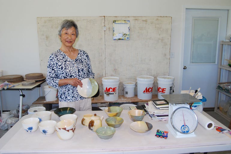 Yoshiko Johnson holds a glazed bowl she created in her pottery studio