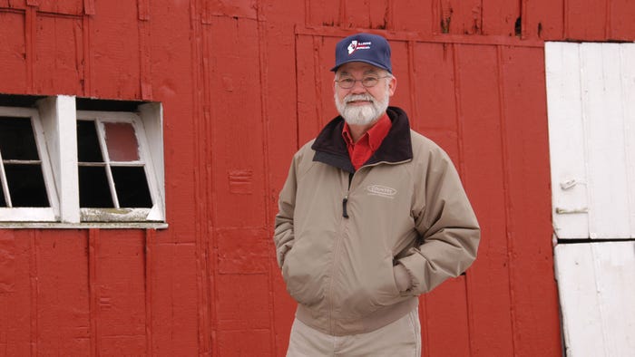 Farmer Terry Pope standing in front of red barn