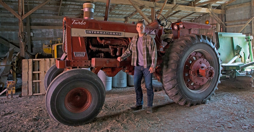Zebediah Davis standing in front of International 1256 tractor