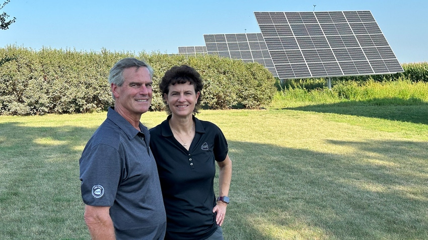 Dale and Lori Stevermer in foreground of field, with solar panels behind them.