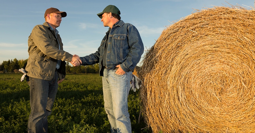 two farmers shaking hands in alfalfa field