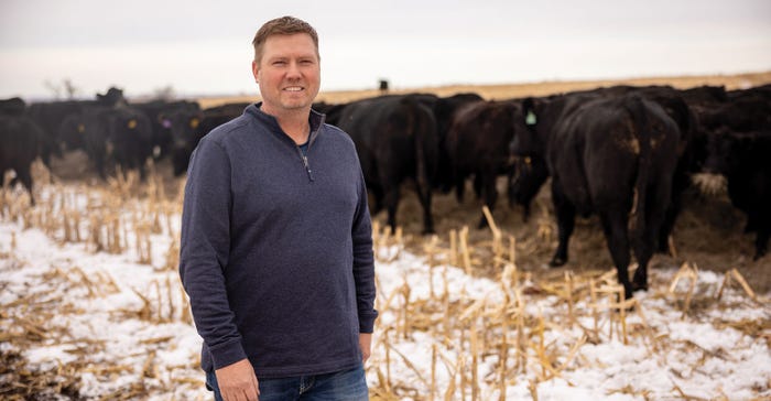 Farmer posed smiling in winter in front of beef cattle