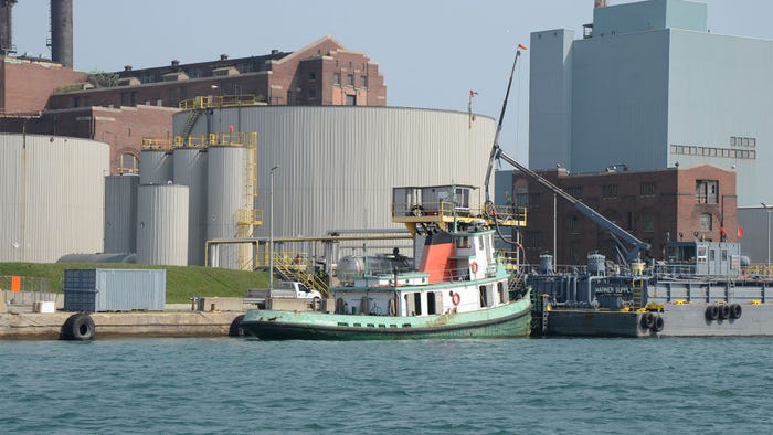 A diesel-burning tugboat parked at a dock near a facility
