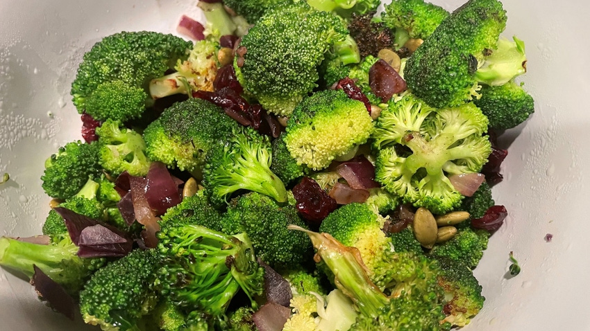 A close-up of broccoli salad with pepitas, red onion and dried cranberries