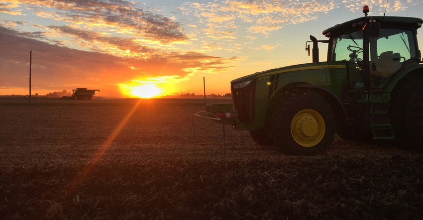 tractor and combine at sunset