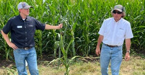 Sam Leskanich holds a short-stature corn plant, standing with professor Fred Below
