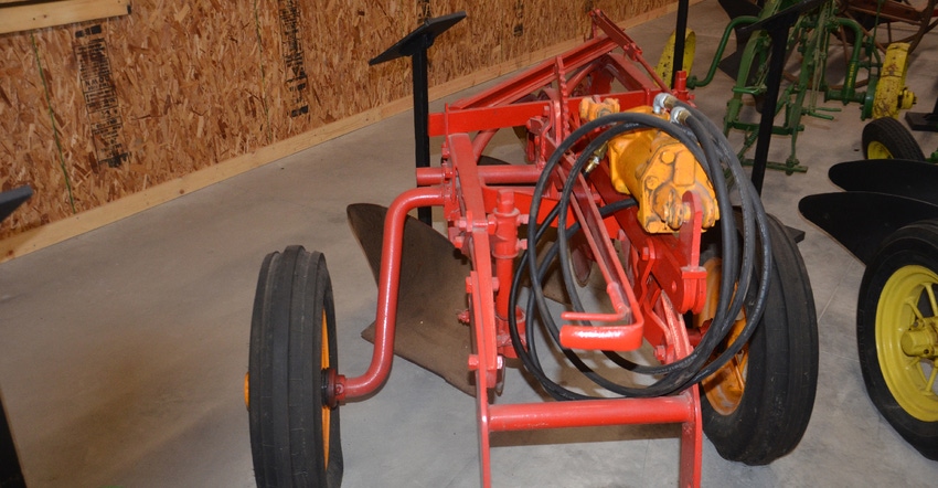 a three-bottom, tractor-drawn plow