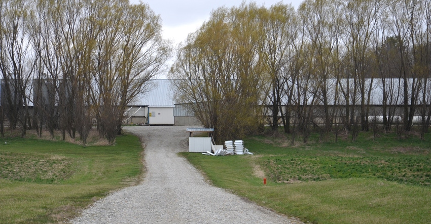 driveway leading to farm building behind trees
