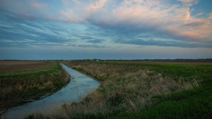 A creek winding through a pasture during a sunset