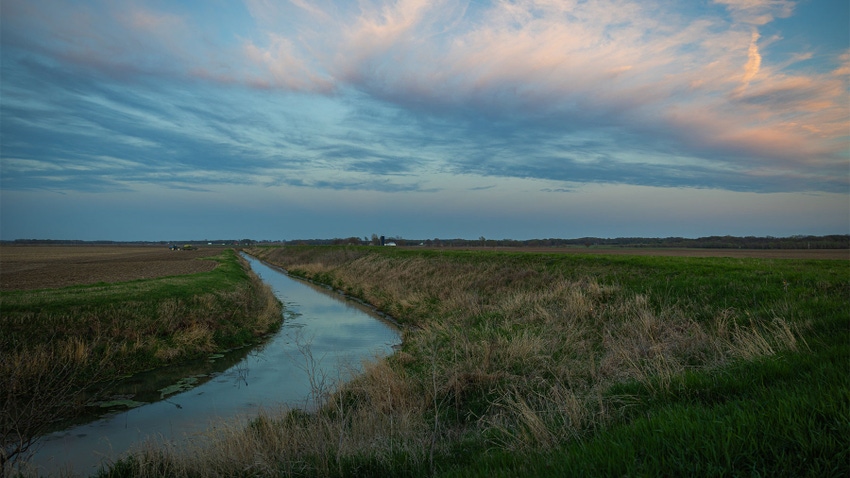 A creek winding through a pasture during a sunset