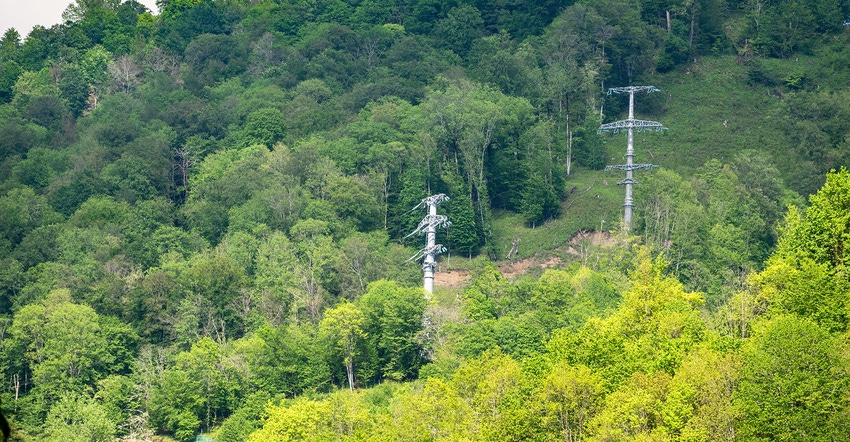 Power lines on a mountain green slope. Overhead power line in the mountains