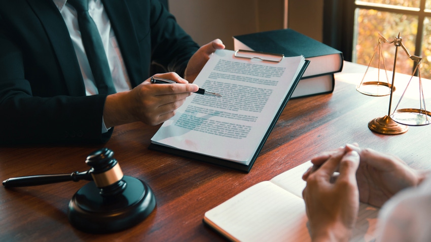 person holding clipboard with papers and pointing with a pen.